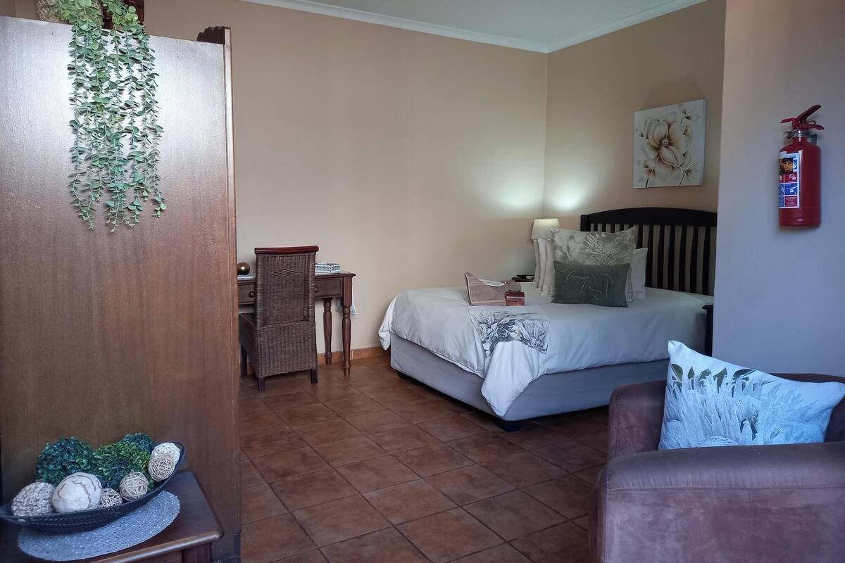 Une chambre à coucher comprenant un lit, une table de chevet, une chaise et un extincteur fixé au mur.