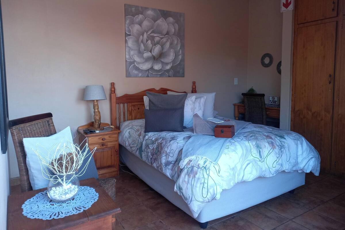 Une chambre à coucher avec un lit, une table de chevet, une lampe et un tableau au mur.