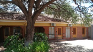 A building with a tiled roof, brick walls, and multiple doors with glass panels. - Acacia Guesthouse (Kathu)
