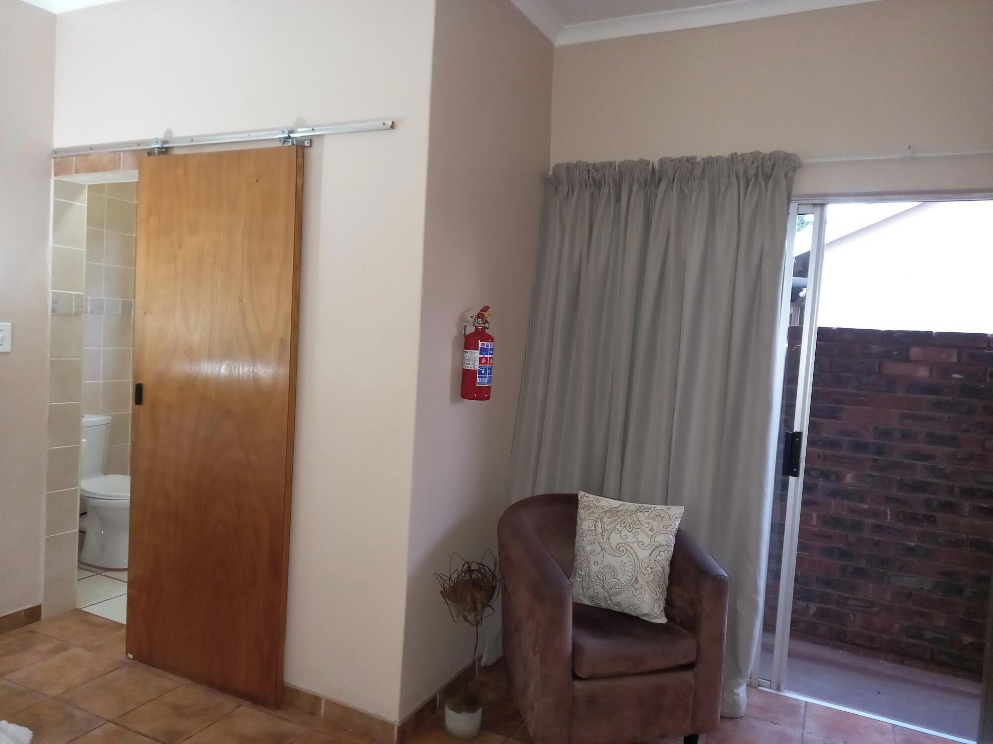 Un baño con puerta de madera, inodoro blanco y zona de ducha.