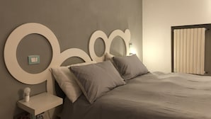 Une chambre à coucher avec un grand lit, une table de chevet avec une lampe et un luminaire fixé au mur.