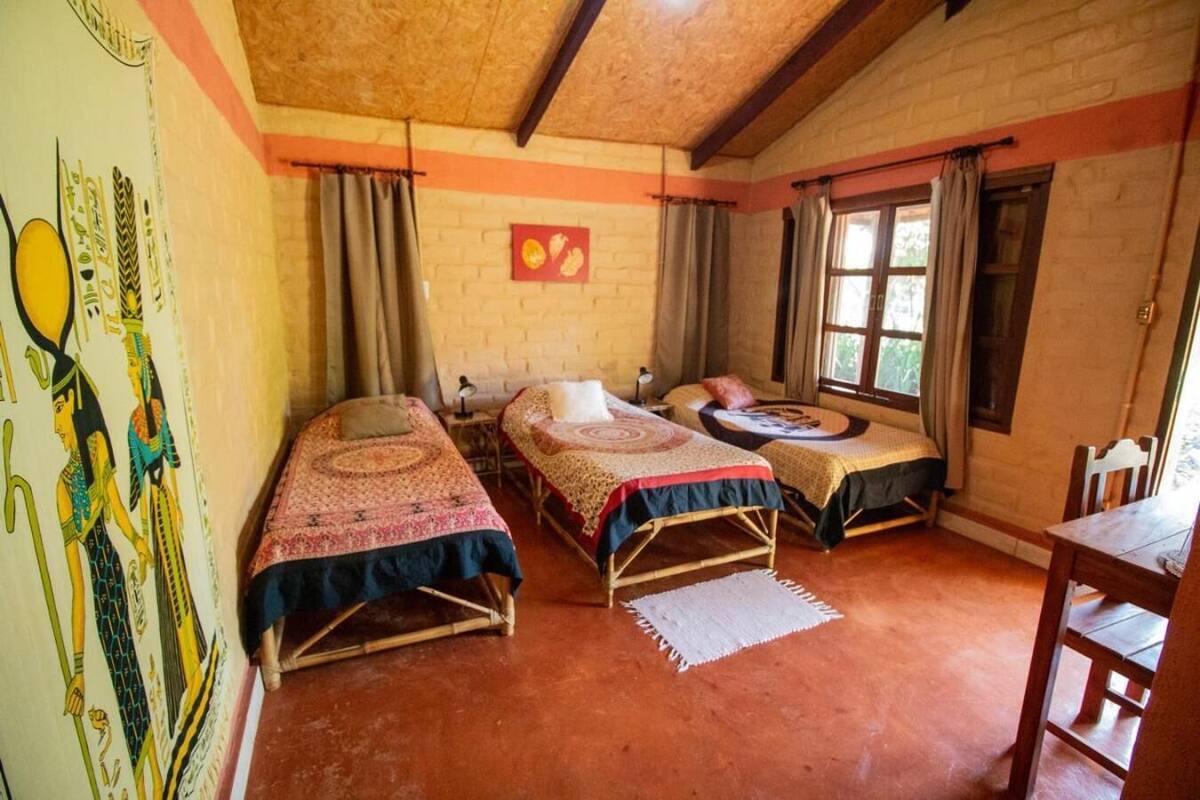Ein Zimmer mit zwei Einzelbetten, einem Holztisch und einem Stuhl.