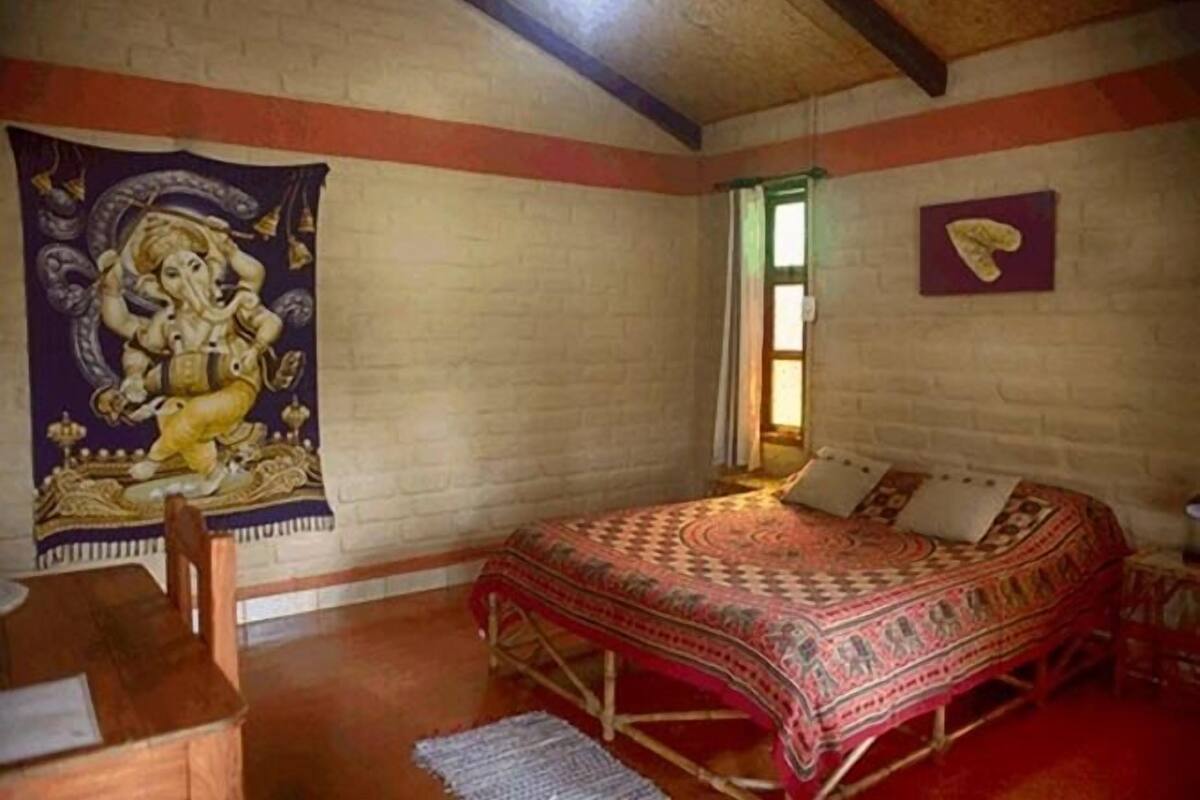 Ein Zimmer mit einem Bett, einem Sessel, einem Wandteppich und einem gerahmten Gegenstand an der Wand.