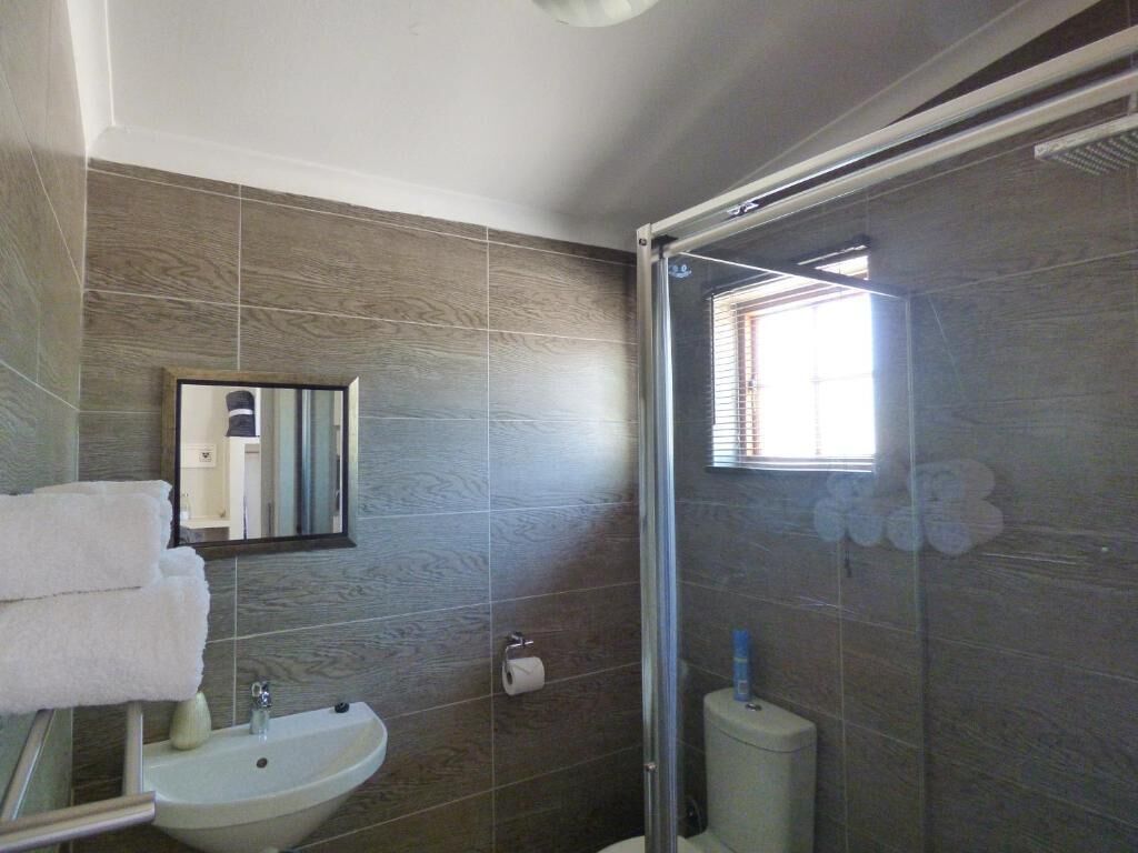 A bathroom with a sink, mirror, and shower.