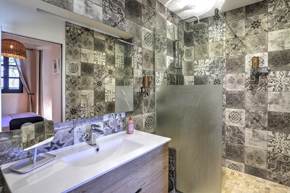 A bathroom with a white sink, a mirror, and a shower area.