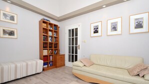 A living room with a sofa, a bookshelf, and framed pictures on the wall.