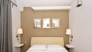 A hotel room with a bed, two bedside tables, two wall-mounted lamps, and three mirrors.
