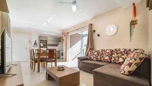 A modern living room with a sofa, coffee table, and dining area. - Aluguel Apartamento 2 quartos sendo 1 suíte - 522 (Bombinhas)