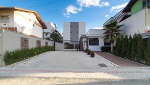 A residential area with modern buildings, a paved driveway, and a gated entrance. - Aluguel Apartamento 2 quartos sendo 1 suíte - 522 (Bombinhas)