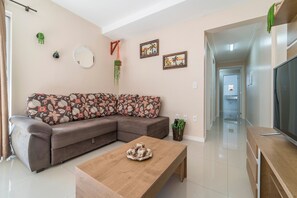 A modern living room with a sectional sofa, a coffee table, and a television. - Aluguel Apartamento 2 quartos sendo 1 suíte - 522 (Bombinhas)