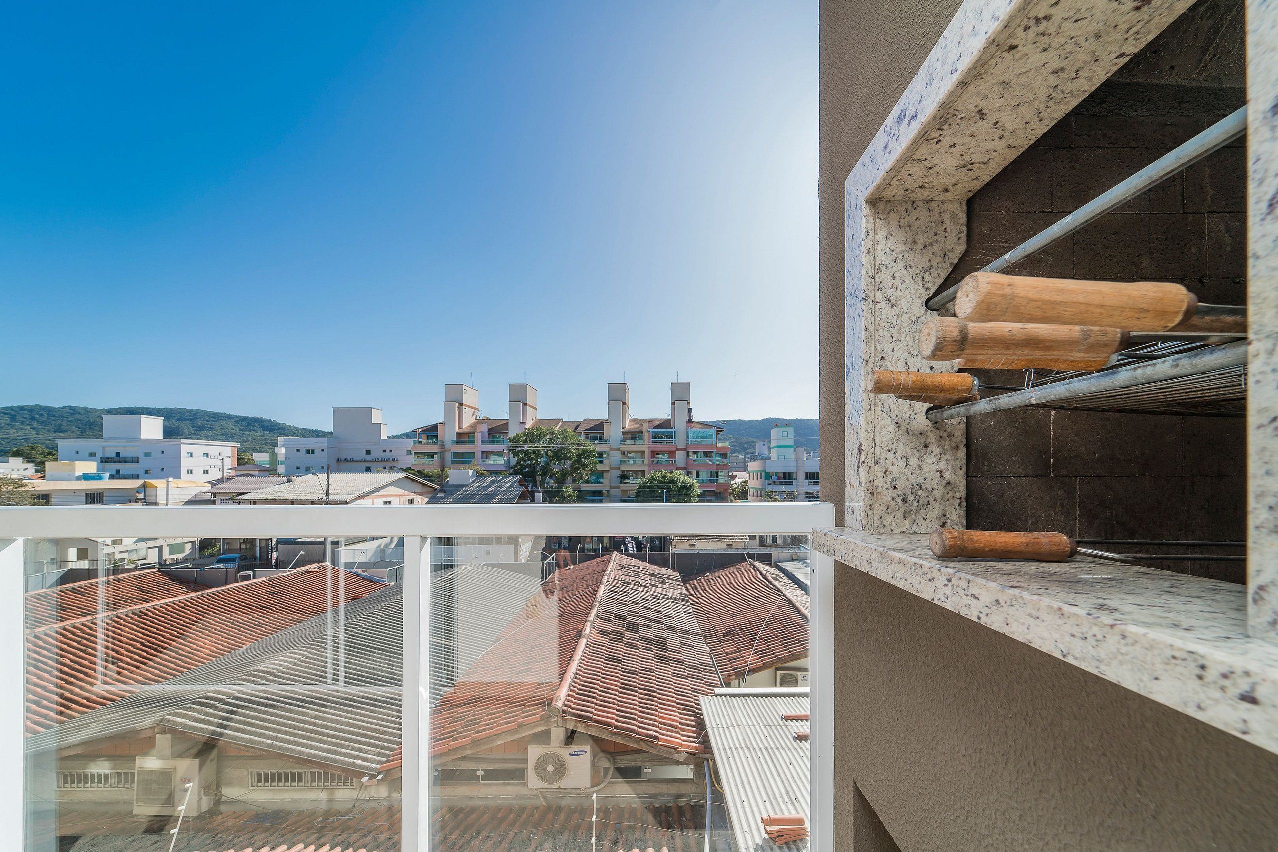Un balcón con vista a un paisaje urbano, que incluye edificios y un cielo despejado.