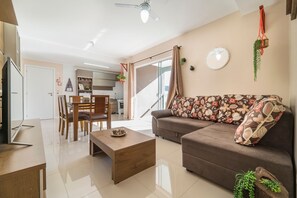 A modern living room with a sofa, coffee table, and dining area. - Aluguel Apartamento 2 quartos sendo 1 suíte - 522 (Bombinhas)