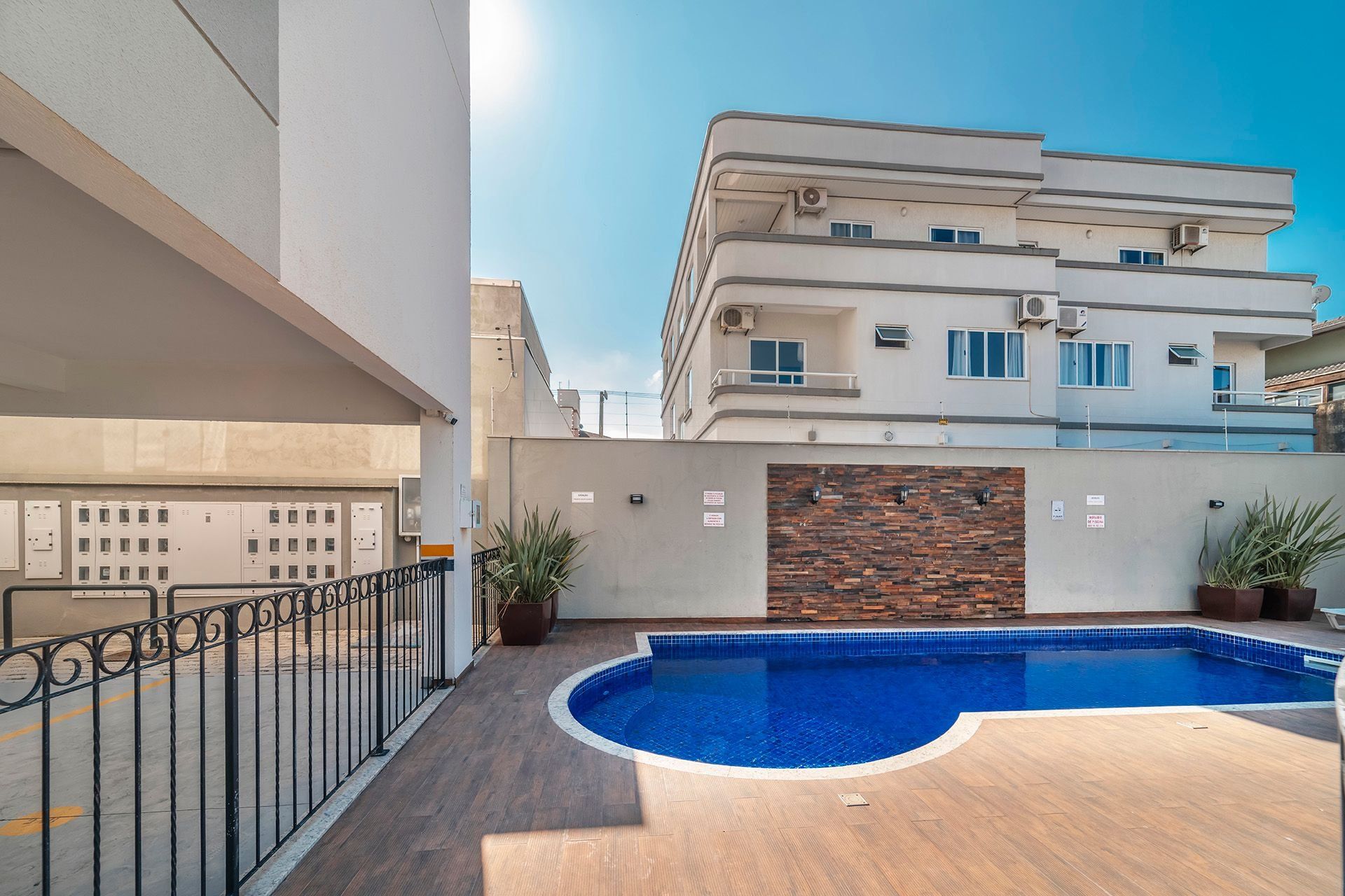Un edificio moderno con piscina, balcón y pared de piedra.