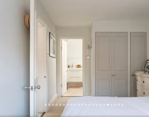 Cozy retreat with a neatly made bed, dresser, and table with a lamp.