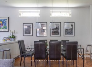 Un espace repas comprenant une table ronde, six chaises et des luminaires suspendus au plafond.