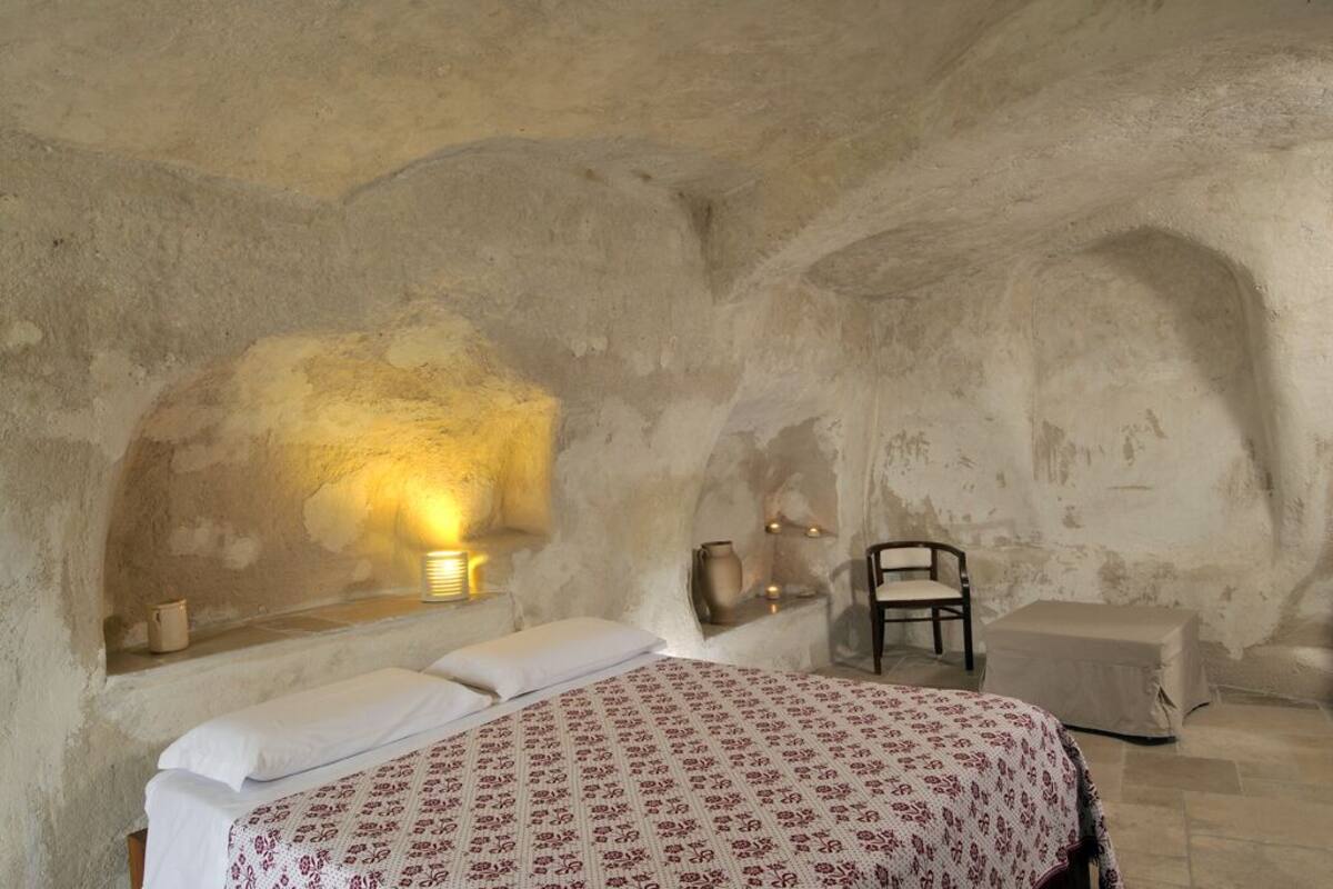 A bedroom with a bed, a chair, and a small table.