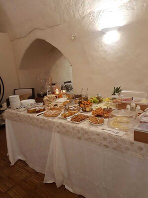 A buffet table with various food items and condiments, set in a room with a textured wall and a wooden floor. - Ai Terrazzini (Matera)