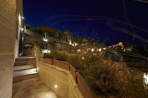 A nighttime view of a historic stone staircase leading up to a building with illuminated windows. - Ai Terrazzini (Matera)