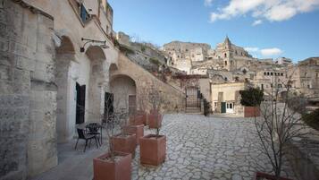 Un cortile con pavimento in pietra, posti a sedere all'aperto e vista su edifici storici sullo sfondo.