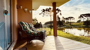 Un espacio de estar al aire libre cubierto con vista a un lago y árboles.