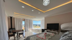 Una habitación de hotel moderna con una cama grande, televisión, escritorio con silla y vistas al exterior.