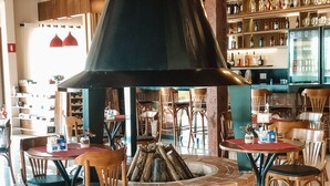 Un restaurante con asientos de ladrillo alrededor de un hogar central, mesas y sillas de madera.