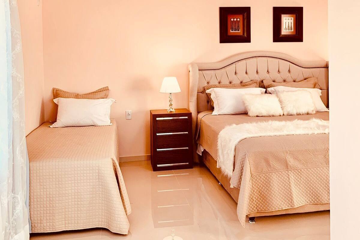 Une chambre avec deux lits, une table de chevet et un luminaire au plafond.