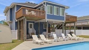 Ein zweistöckiges Haus mit überdachter Terrasse und Swimmingpool.