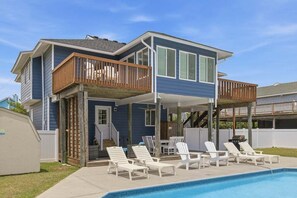 Ein zweistöckiges Haus mit überdachter Terrasse und Swimmingpool.