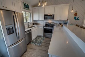 Enjoy cooking in this well-equipped kitchen with stainless steel appliances, white cabinetry, and a toaster.