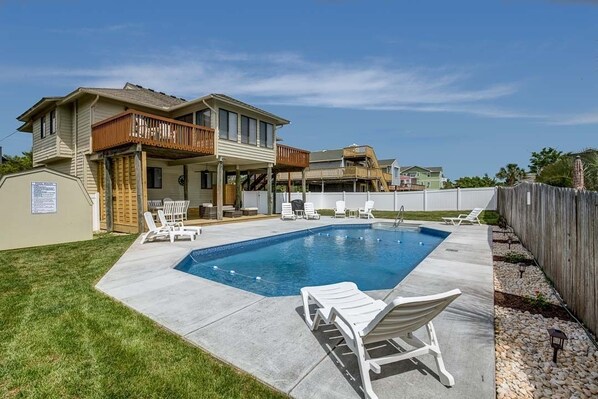 Relax by the pool in the spacious backyard, complete with lounge chairs and a well-manicured lawn.