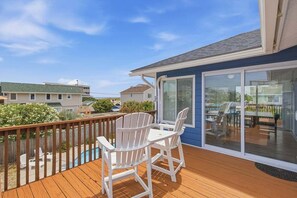 Eine Terrasse mit weißen Adirondack-Stühlen, einem Pool und Blick auf benachbarte Häuser.