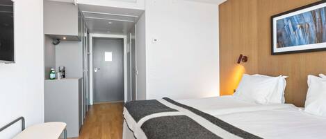 Ein Hotelzimmer mit Bett, Schreibtisch, Stuhl, Kleiderschrank und einem Gemälde an der Wand.