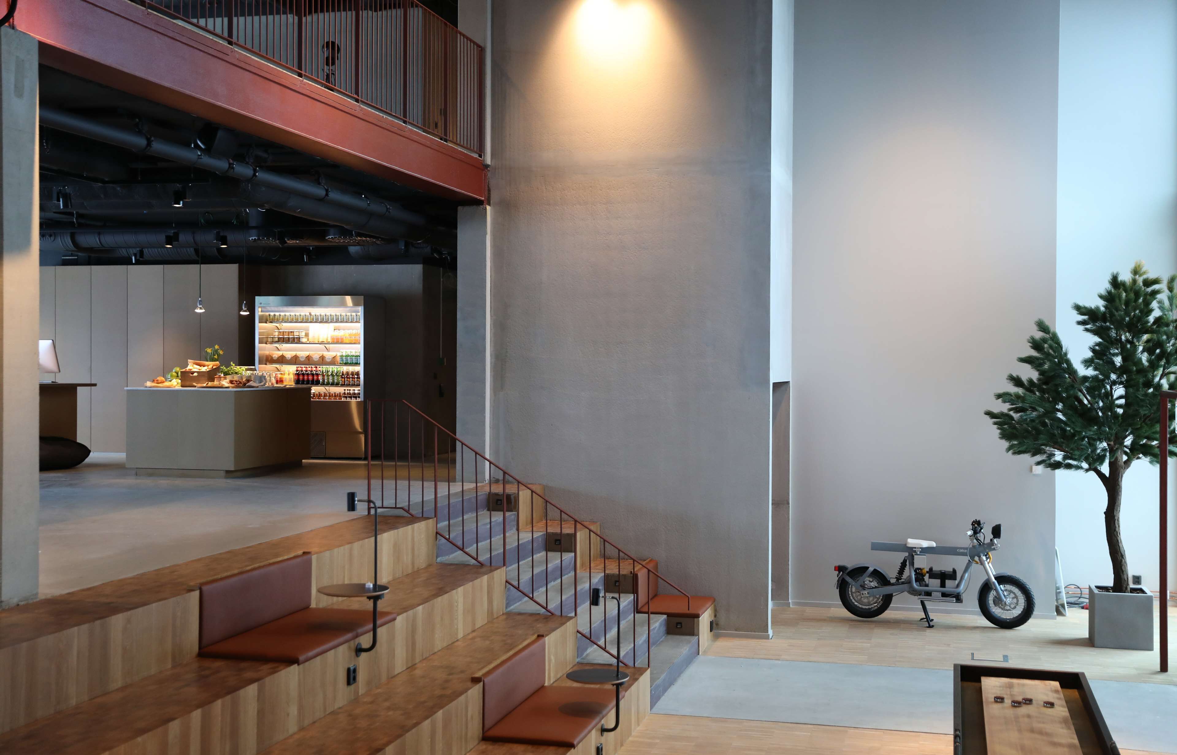 A modern interior with a staircase, a seating area, a small table, a motorcycle, and a plant.