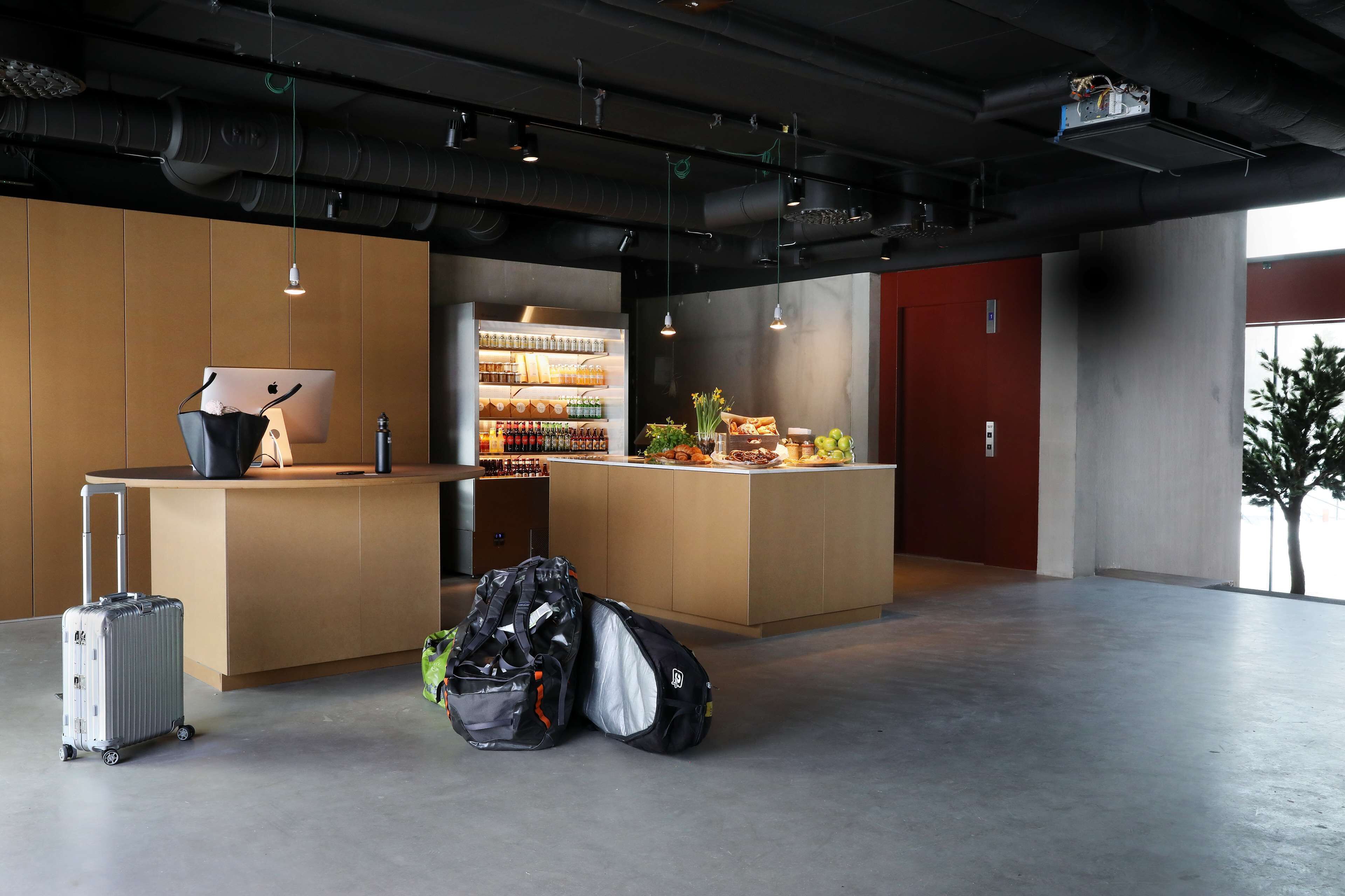 En modern hotellobby med en receptionsdisk, en minibar och en sittgrupp.