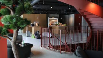 A modern interior with a staircase, seating area, and a refrigerator stocked with beverages.