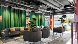 Un interior moderno con un telón verde de fondo, un sofá y dos sillones.