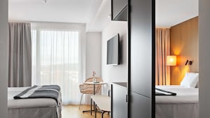 Habitación de hotel con dos camas, un escritorio, una silla, un televisor y una lámpara.
