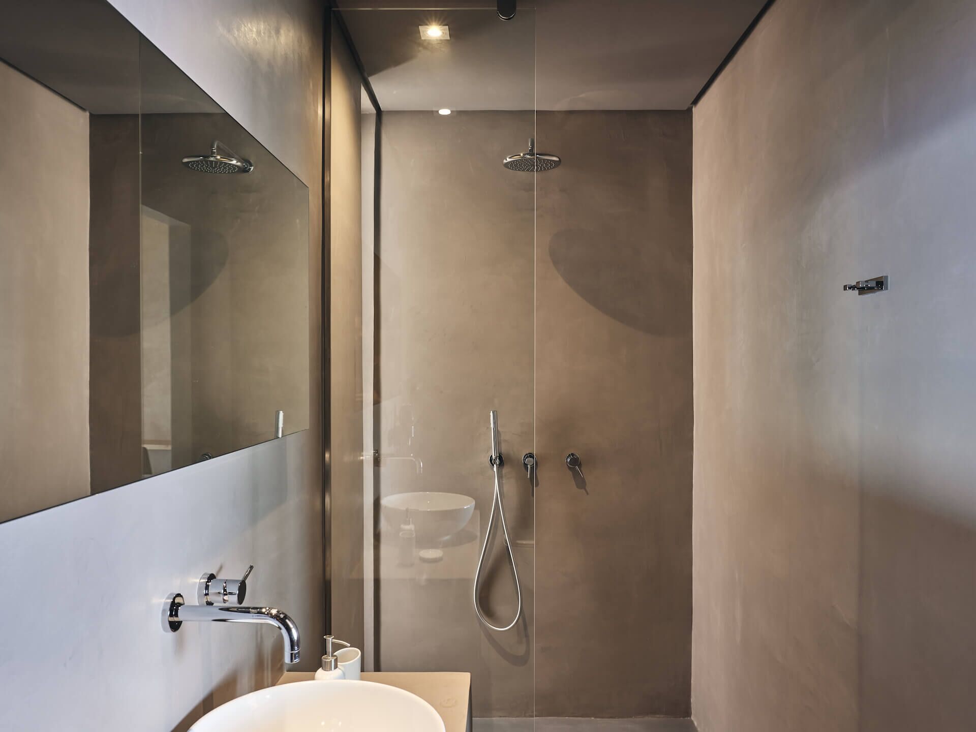 A modern bathroom with a glass shower enclosure, a large mirror, and a white sink.