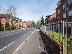 Een woonstraat met bakstenen huizen, een heldere weg en een hek aan één kant.