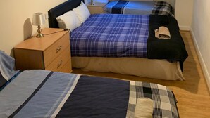 Ein Hotelzimmer mit zwei Betten, einem Nachttisch, einer Lampe und einem Fenster mit Vorhängen.