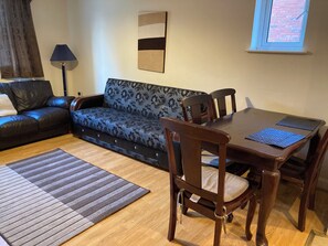 Een woonkamer met een bank, een eettafel en een vloerkleed.