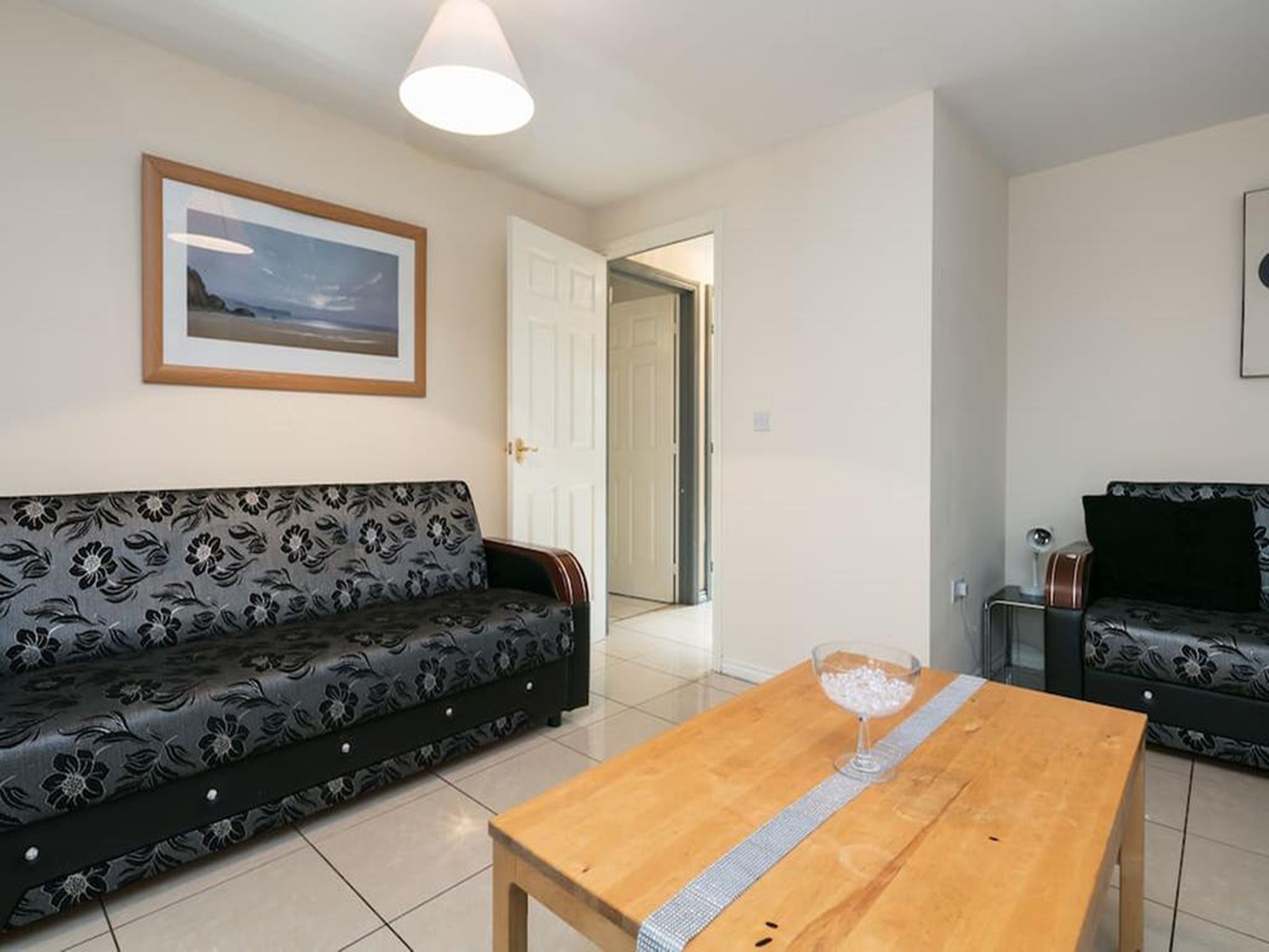A living room with a sofa, a coffee table, and a door leading to another room.