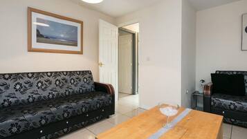 A living room with a sofa, a coffee table, and a door leading to another room.