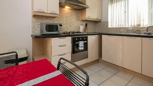 Une cuisine compacte équipée d’un four à micro-ondes, d’une cuisinière, d’un four et d’une fenêtre avec des rideaux.