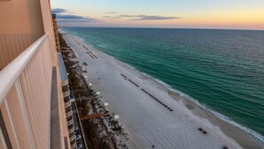 A beach view from a balcony overlooking a sandy beach with a clear sky.