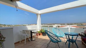 A covered patio with a table and chairs, a view of the cityscape, and a tiled floor. - Marino house, your beach house (san francesc, formentera)