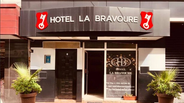Das Hotel La Bravoure mit moderner Fassade, zwei Pflanzkübeln und einem sichtbaren Eingang.