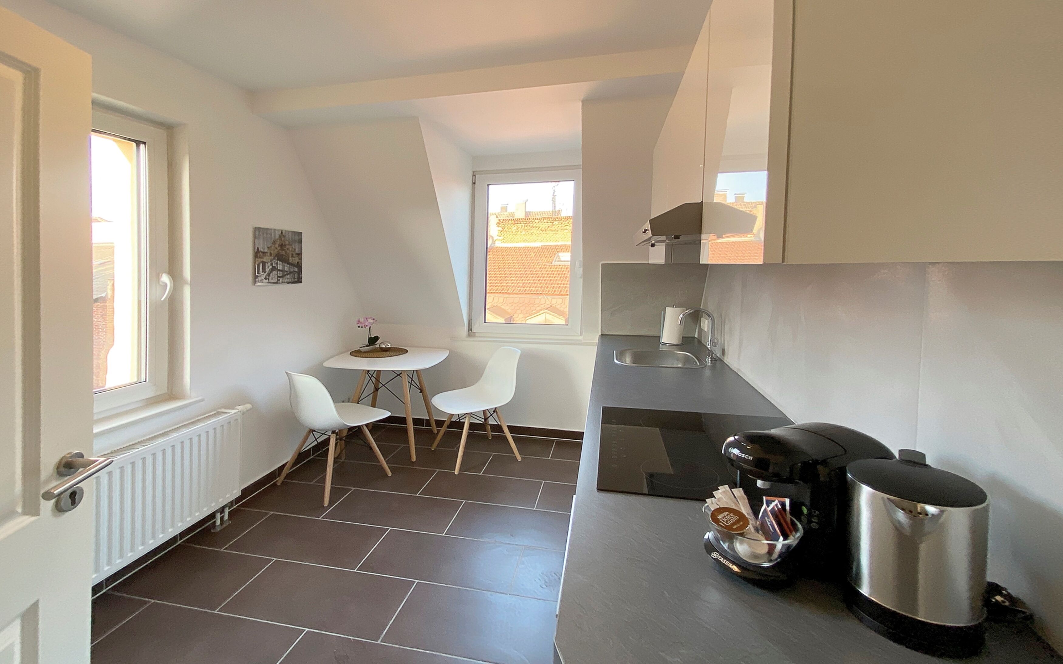 A compact kitchen with a dining area, a window, and a radiator.