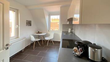 A compact kitchen with a dining area, a window, and a radiator.